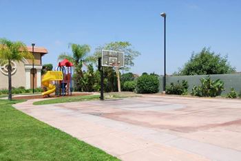 A basketball court with a yellow slide in the background.